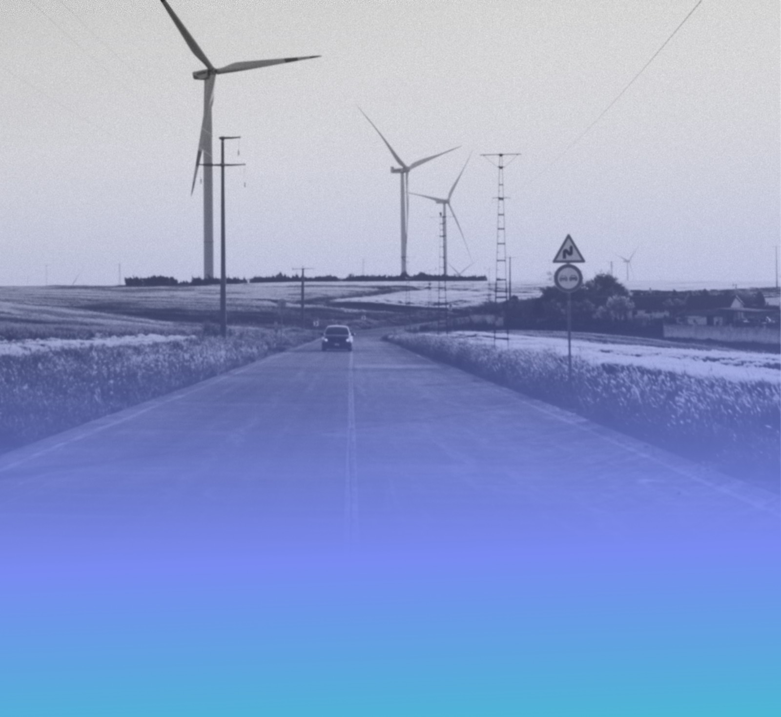 Wind turbines beside a country road at golden hour